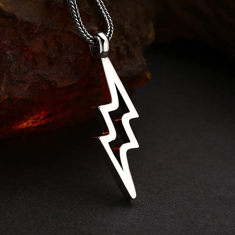 Side‑perspective polished 925 sterling silver hollow lightning bolt men pendant necklace on rustic stone backdrop
