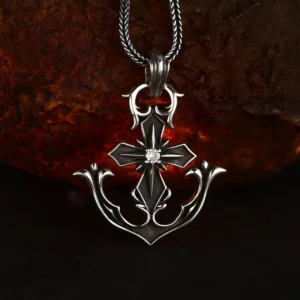 Vintage oxidized 925 sterling silver anchor cross pendant with center stone inlay, attached to silver wheat chain against rustic rock background