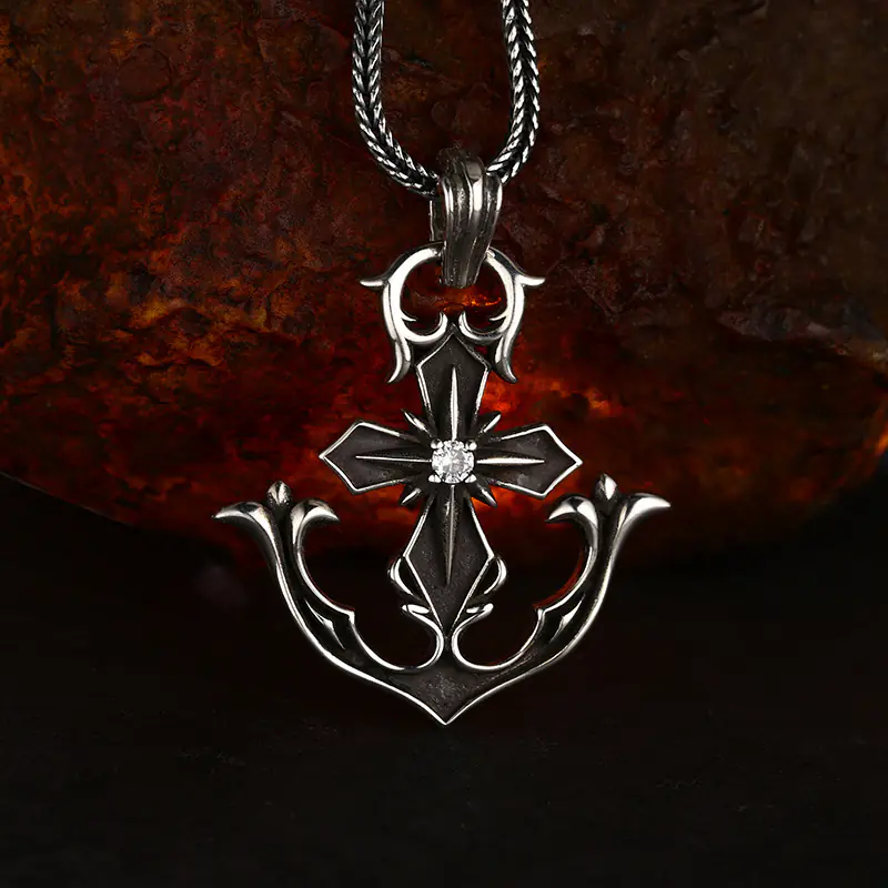 Vintage oxidized 925 sterling silver anchor cross pendant with center stone inlay, attached to silver wheat chain against rustic rock background