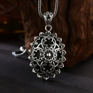 Antique oxidized 925 sterling silver mandala filigree oval pendant, black enamel floral openwork design against natural wood texture background