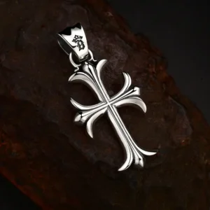 Tilted flat‑lay view 925 sterling silver gothic fleur‑de‑lis cross pendant, shows sculpted contours and engraved logo on decorative bail