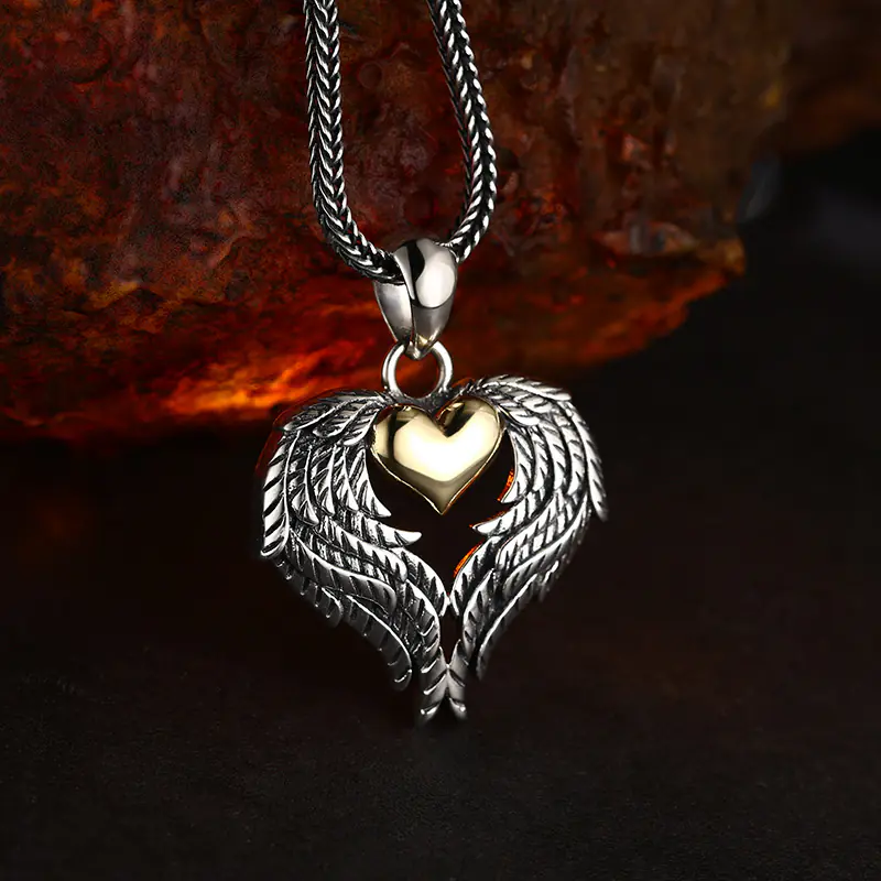 Slight side‑angled shot of two‑tone 925 silver angel wing gold heart pendant, displaying three‑dimensional carved feather relief details