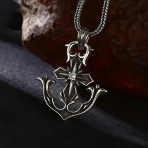 Retro 925 sterling silver anchor cross pendant with center stone, laid over dark fabric and textured rust rock backdrop
