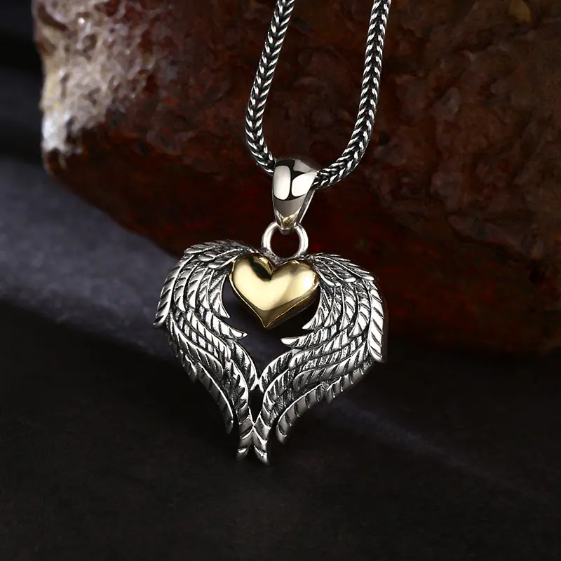3-two‑tone‑925‑silver‑angel‑wing‑gold‑heart‑pendant‑dark‑fabric‑rust‑rock‑atmospheric‑lifestyle.jpg Atmospheric lifestyle shot two‑tone 925 sterling silver angel wing gold heart pendant over dark fabric and rustic rock backdrop