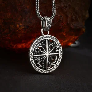 Atmospheric lifestyle shot open‑work star‑compass 925 sterling silver medallion pendant on dark flat surface with rustic rock backdrop