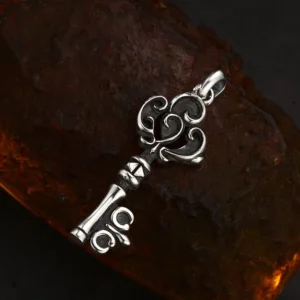Flat lay shot vintage scroll key 925 sterling silver charm on rough stone